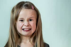 close up portrait of little girl with long hair making a disgusting impression